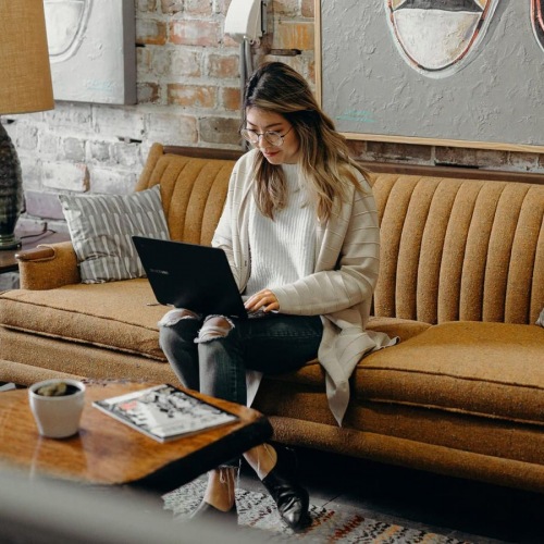 Gorgeous natural light in your living space a woman sitting on a couch working on a laptop