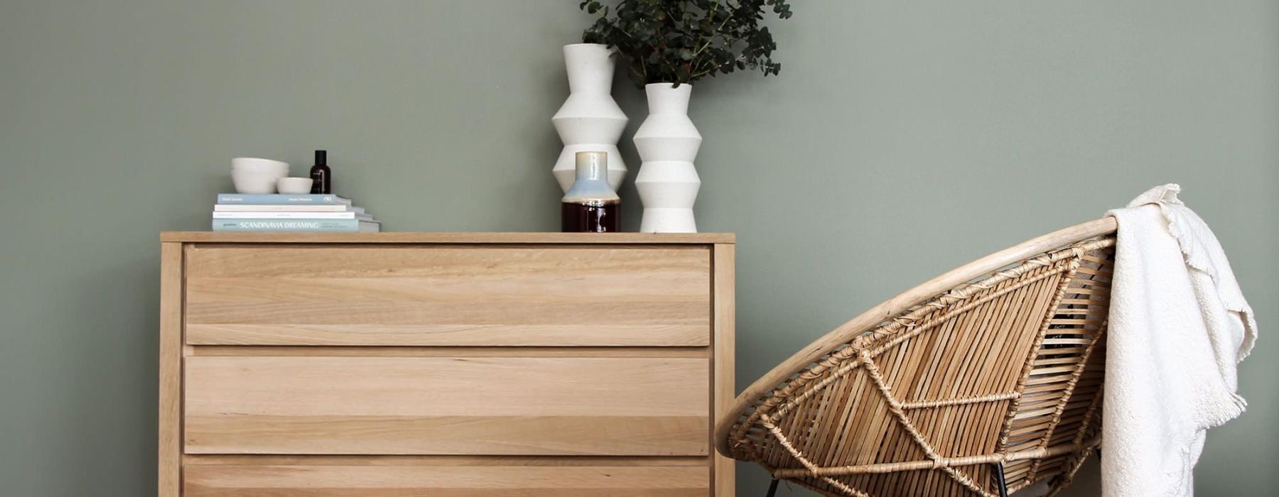 decor on a tall, wooden dresser next to a papasan chair with a throw